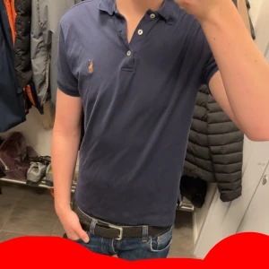 Mörkblå piké från Polo Ralph Lauren - Mörkblå pikétröja från Polo Ralph Lauren med klassisk krage, korta ärmar och broderad logga på bröstet. Modellen är custom slim fit och har knappar framtill. Perfekt för en clean och stilren look. Priset e inte hugget i sten så kan gå ner vid snabb affär. Den är storlek s men passar M också