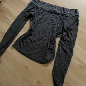 Svart offshoulder topp från BikBok - Svart offshoulder topp från BikBok i mjukt bomullsmaterial. Toppen har långärmade smala ärmar och en bred kant upptill som ger en snygg offshoulder-look. Perfekt att styla med jeans eller kjol för en trendig vibe. 