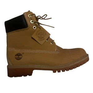 Timberland klassiska boots beige - Säljer ett par ikoniska Timberland boots i beige mocka med robust gummisula och snörning i guld. Skorna har svart vadderad kant upptill och tydliga Timberland-loggor på sidan och sulan. Perfekta för höst och vinter, med slitstark design och rund tå.