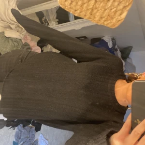 Svart stickad tröja från 157 - En svart stickad tröja från 157 med rund hals och ribbade muddar vid ärmslut och nederkant. Tröjan har en klassisk, enkel design och är långärmad, perfekt för att hålla dig varm under kyliga dagar. Passar dig som gillar stilrena och bekväma plagg.