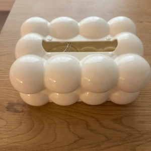 Vit bubblig  - Unik servetthållare  i vit färg med coolt bubbligt mönster och rektangulär form. Servett hållaren har ett öppet fack upptill och är perfekt för dig som vill sticka ut med en trendig hem inredning