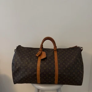 LV Keepall 60  - Louis Vuitton Keepall 60 i vintageskick. Väskan är i bra vintageskick och finns mycket liv kvar i den. Däremot finns de fläckar inuti väskan samt lite skavanker på metalldelar. Axelband medföljer, har ni frågor eller funderingar så hör av er.