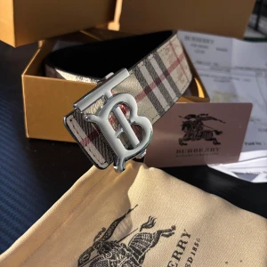 Burberry vändbart bälte giftbox - Säljer ett vändbart Burberry-bälte i kalvskinn med klassiskt rutigt mönster i beige, svart och rött på ena sidan och svart med diskret rutmönster på andra. Stort silvrigt B-spänne framtill. Kommer med originalbox, dustbag och certifikat.