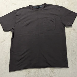 Brun t-shirt från The Black Label Collection Lager 157 - En basic brun t-shirt från The Black Label Collection Lager 157 med rund halsringning och en bröstficka. T-shirten är i mjuk bomull och har en klassisk passform med korta ärmar. Perfekt för en clean, enkel stil och för vardagen! 