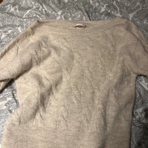Beige stickad tröja från Gina Tricot - Mysig beige stickad tröja från Gina Tricot i storlek S. Tröjan har ett klassiskt kabelstickat mönster, rund halsringning och långa ärmar med breda ribbade muddar. Perfekt för lager-på-lager under kyliga dagar. Aldrig använd‼️