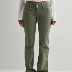Gröna bootcut byxor med hög midja - Snygga gröna byxor med bootcut-modell och hög midja. Byxorna har klassisk femficksdesign, två knappar i midjan och raka ben som blir vidare nertill. Perfekta för en trendig och avslappnad look. använda en gång(nypris 699)