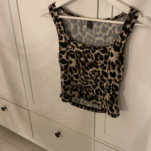 Leopardmönstrad linnetopp från SHEIN - Snygg linnetopp från SHEIN i leopardmönster med beige och svarta toner. Toppen har ärmlös design och rund halsringning, perfekt för att sticka ut med en trendig look.