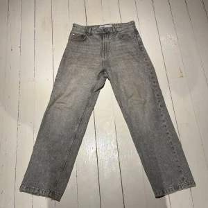 Grå raka jeans från Bershka - Grå jeans från Bershka med rak passform och klassisk femficksdesign. Jeansen har hög midja och är tillverkade i ett slitstarkt bomullstyg med snygg tvättad look. Perfekta för en avslappnad och trendig stil. INGET FAST PRIS