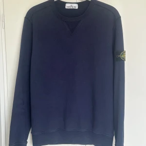 (Äkta) Blå Stone Island Crewneck - Snygg och stilren crewneck från Stone Island i storlek L (passar M). Tröjan är sparsamt använd och därför i mycket fint skick. Tveka inte på att meddela mig om du har minsta fråga!