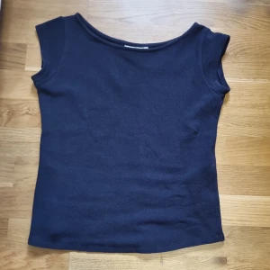Mörkblå stickad topp från Boomerang - Säljer en mörkblå stickad topp från Boomerang i storlek M. Toppen har en enkel, ärmlös design med rundad halsringning och är tillverkad i ett grovstickat material som ger en snygg struktur. Perfekt för dig som gillar stilrena och klassiska plagg.