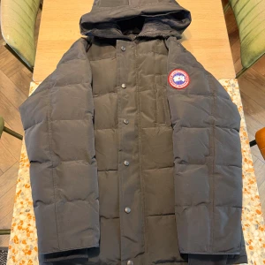 Ganada goose carson parka  - Säljer en svart dunjacka från Canada Goose i storlek L. Jackan har huva, quiltad design och klassisk logotyp på ärmen. Stängs med både dragkedja och knappar. Perfekt för kalla vinterdagar och riktigt snygg streetstil.