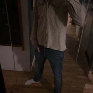 Overshirt Jack and Jones  - Snygg beige overshirt  med klassisk krage och knappar framtill. Skjortan har två bröstfickor med lock och långa ärmar. Perfekt för dig som gillar en enkel och stilren look. Passar till jeans eller chinos för en avslappnad vibe.