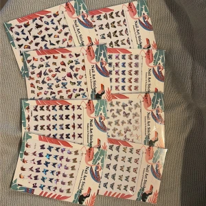 Färgglada fjärils-nagelstickers - Säljer 8 ark med nagelstickers i form av fjärilar i olika färger och mönster. Perfekt för att skapa unika och kreativa nageldesigner. Stickersarna har metallic och holografiska effekter och kommer i både små och större storlekar. Superenkla att använda för att piffa upp dina naglar.