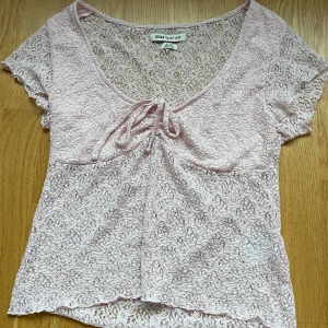 Ljusrosa spetsblus  - Säljer en ljusrosa blus från Urban Outfitters i genombruten spets med v-ringning och söt knytning framtill. Storlek XL men passar M också💕