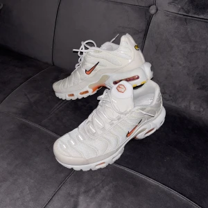 Nike Air Max Plus vita sneakers - Nike Air Max Plus sneakers i vit mesh med syntetdetaljer och orange detaljer på sula och logga. Snygg design med synlig Air-enhet, snörning och rund tå. Ikonisk TN-logga på hälen och undersidan. Perfekt för dig som gillar streetwear och sportig stil. Nypris 2199 kr. Hör gärna av er vid frågor🤩