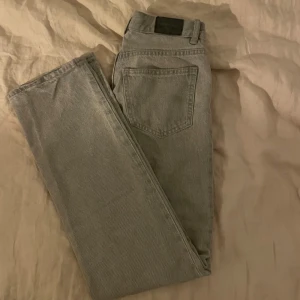 Raka gråa jeans  - Säljer ett par grå jeans från Levi's med klassisk rak passform och femficksdesign. Jeansen har en enkel look med bakficka och svart patch i midjan. Perfekta för dig som gillar stilrena och tidlösa byxor.