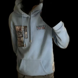 Ljusblå hoodie från Supply & Demand - Säljer en ljusblå hoodie från Supply & Demand med tryck av palmer och textdetaljer. Hoodien har en stor ficka framtill och justerbar huva. Perfekt för en avslappnad stil. 170-180