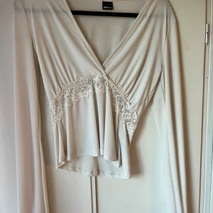 Vit v ringad topp med lite spets från gina - En v ringad topp från Gina tricot, använd 1 gång och den har en söt spets på magen