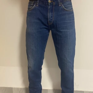 Blå jeans från J.Lindeberg 32/32 - Snygga blå jeans från J.Lindeberg i klassisk rak modell. Jeansen har fem fickor, kontrastsömmar och normal passform. Tillverkade i slitstarkt denimtyg som ger en cool och tidlös look. Perfekta för dig som gillar stilrena och enkla jeans.