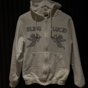  BlingLucid zip up - Vit hoodie med dragkedja och huva från Bling Lucid. Tröjan har snörning vid huvan och är i nyskick endast använd få gånger, Storlek S har även en svart i samma stil och storlek 