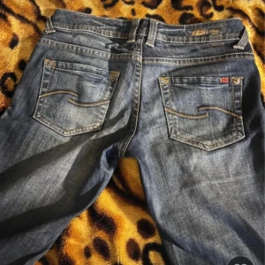 QS Abby bootcut jeans blå W32 - Snygga blå Abby jeans från QS by s.Oliver med bootcut passform och låg midja. Klassisk femficksmodell med dekorativa sömmar på bakfickorna och tydliga kontrastsömmar. Jeansen har knapp och dragkedja fram samt etikett i rött på insidan. Köpta i vinted. Säljer p.g.a att de är för små. Pris kan diskuteras.