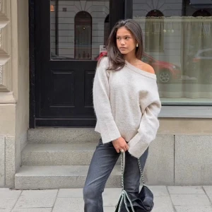 Beige offshoulder stickad tröja - Supermjuk och oversized stickad tröja i beige med offshoulder-design. Tröjan har breda muddar vid ärmslut och nederkant, samt en avslappnad passform som ger en chill vibe. Perfekt för lager-på-lager och snygg till både jeans och kjol. Nästan aldrig använd