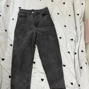 Svarta högmidjade jeans från Levi's - Snygga svarta jeans från Levi's med hög midja och klassisk femficksdesign. Jeansen har raka ben och silverfärgad knapp framtill. Perfekt för dig som gillar en enkel och stilren look.