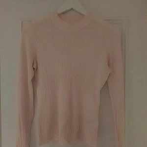 Ljusrosa ribbad tröja från H&M - Säljer en ljusrosa ribbad långärmad tröja från H&M i storlek M. Tröjan har en rund hals och är figurnära med stretchigt material. Perfekt för dig som gillar en enkel men snygg look med mjuk känsla.