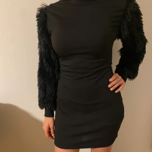 Svart klänning med fluffiga ärmar - Säljer en svart kortklänning med höghalsad design och långa, fluffiga ärmar som ger en unik look. St M/L men passar även S 