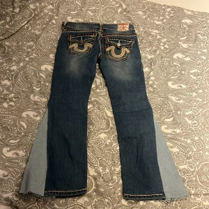 True Religion bootcut jeans blå, stl 27 - Säljer ett par blå bootcut jeans från True Religion med kontrastsömmar och broderade bakfickor. Dem är begagnade så dem är använda. 