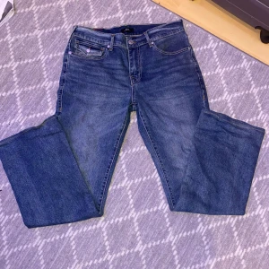 True Religion blå bootcut jeans - Säljer ett par klassiska blå jeans från True Religion med bootcut passform. Jeansen har ikoniska bakfickor med kontrastsömmar och tryckknappar, samt en tydlig True Religion-patch bak i midjan. Tillverkade i slitstarkt denim med snygg tvätt. Har klippt där nere på byxor har sytt om för att passa bättre, men de är fortfarande asså långa🤟🏽har använt de kanske 4 gånger 