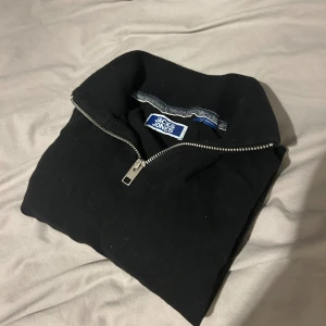 Svart half zip-tröja Jack & Jones - Svart långärmad tröja från Jack & Jones med half zip-dragkedja och hög krage. Tröjan har en clean look och är tillverkad i mjukt material som passar perfekt till jeans. Enkel och stilren design som funkar året runt.