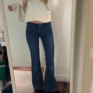 Blå bootcut jeans från MiH Jeans - Snygga blå bootcut jeans från MiH Jeans i klassisk denim. Medelhög midja och utsvängda ben ger en retrovibe. Jeansen har fem fickor, bälteshällor och guldfärgade detaljer. Lite slitningar vid skrevet!