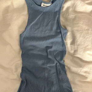 Blå ribbad linnetopp från Weekday - Säljer en ljusblå ribbad linnetopp från Weekday i storlek XS. Toppen är ärmlös med rund halsringning och har en slim passform. Materialet är mjuk bomull med stretch och den har en enkel, stilren look som är lätt att matcha.