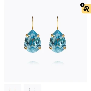 Blå droppformade örhängen i guld - Snygga örhängen med stora, droppformade blå stenar infattade i guldfärgade krokar. Stenarna har en glittrig finish som fångar ljuset och ger ett lyxigt intryck. Perfekta för dig som vill sticka ut med färg och elegans. Dom är ifrån caroline svedbom och är aldrig använda då dom inte passade min smak. Orginalbox finns kvar kan skicka bilder privat på örhängena med. Köpt för 795!❤️