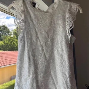 Vit spetsblus med volangärm - Superfin vit blus från Pieces (Veromoda)  med spetsmönster och dekorativa volangärmar. Perfekt för sommarens alla tillfällen, med ett romantiskt och fräscht uttryck.