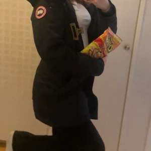 Svart dunjacka från Canada Goose - Svart dunjacka från Canada Goose med klassisk patch på ärmen och snyggt spänne framtill. Jackan är lång och har quiltad design, perfekt för kalla dagar. Fodrad med dun och har långa ärmar med ribbade muddar. En ikonisk vinterjacka med grym passform. Den är lite sönder längst ner vid ärmarna där av det billiga priset, päls följer med, fler bilder finns bara att skriva ! 