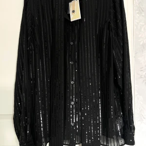Michael Kors blus paljetter - Helt ny med prislapp kvar  En skarfliknande knytning framtill  Storlek L men skulle även passa M och S, smaksak vad man gillar för passform   Nypris: ca 3000kr   55% Recycled polyester  45% Polyester 
