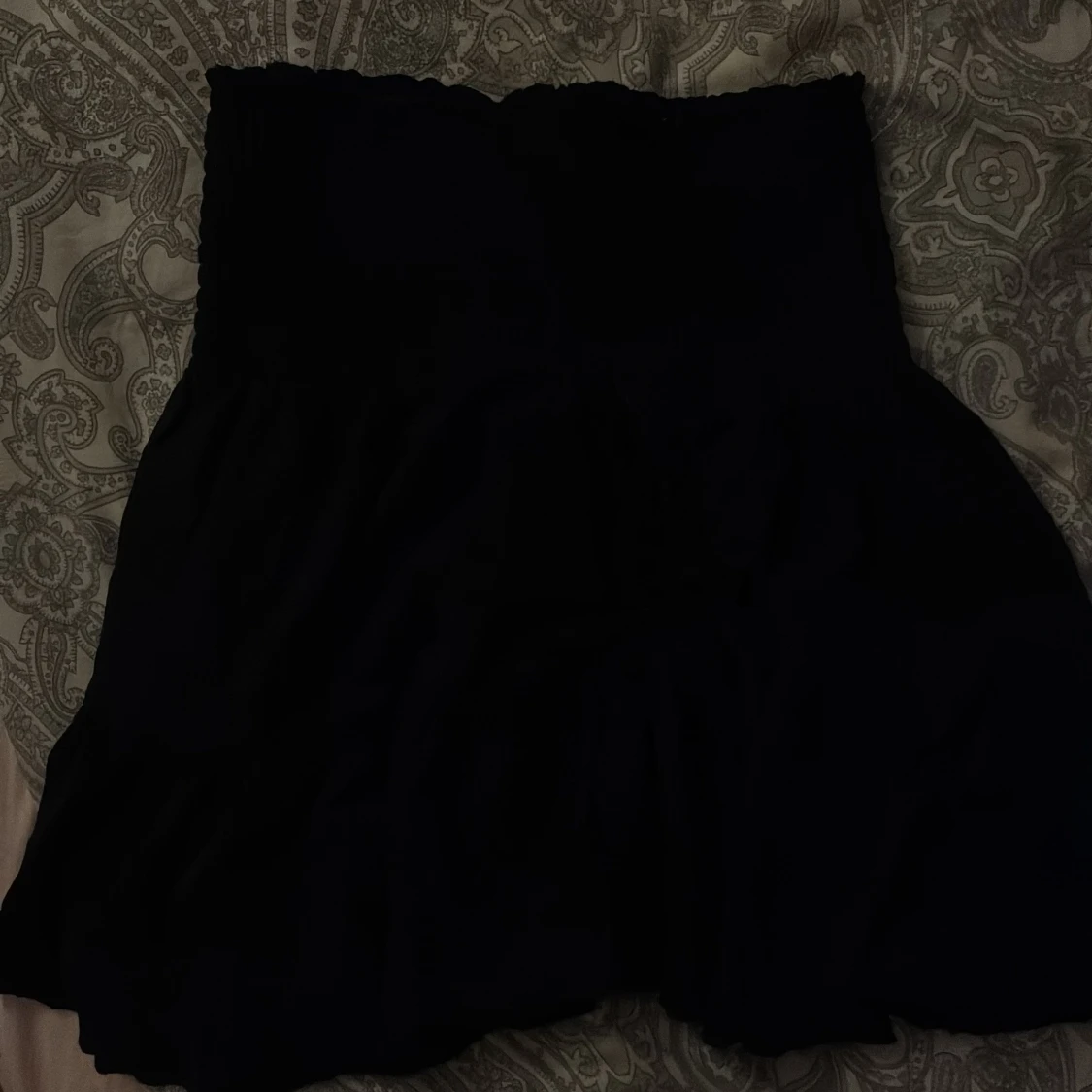 Svart kortkjol med smockad midja