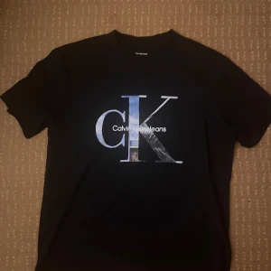 Svart t-shirt från Calvin Klein Jeans - (Använd i endast 1 dag!) Snygg svart t-shirt (relativt oversized) från Calvin Klein Jeans med stort CK-tryck. Kostar över  400kr som ny, så här får du en pris minskning fast med precis samma skick. 