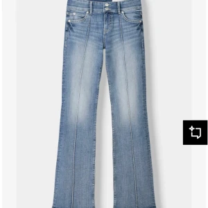 Bootcut ljusblå jeans med pressveck - Snygga ljusblå bootcut jeans med markerade pressveck längs benen och dubbla knappar i midjan. Jeansen har klassisk femficksdesign och är tillverkade i mjukt denimtyg med lätt tvättad look. Perfekta för dig som gillar retrovibbar och bekväm passform.