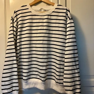 Randig sweatshirt i XXL, H&M - Vit sweatshirt med svarta horisontella ränder i oversized passform i nyskick. Mjuk insida och ribbade muddar vid ärmslut och nederkant. Perfekt för chill dagar och enkel att matcha med jeans eller joggers. 