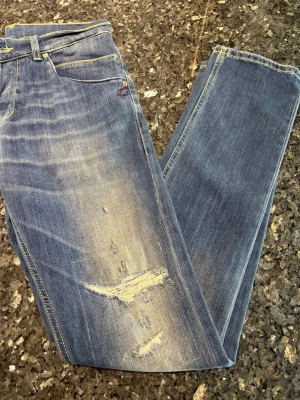 Dondup jeans  - Snygga blå dondup jeans med slitningar och ljusa partier framtill. Raka ben och klassisk femficksmodell. Gula kontrastsömmar och detaljer vid bakfickan. Perfekta för en avslappnad och trendig look. Skirv vid frågor eller längd
