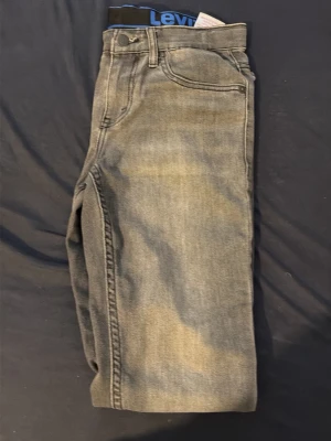 Grå jeans från Levi's - Snygga grå jeans från Levi's med klassisk femficksdesign och raka ben. Jeansen har en diskret tvättad look och är tillverkade i denim. Perfekta för en avslappnad och trendig stil.