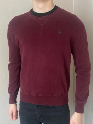 Vinröd tröja från Ralph Lauren - Snygg vinröd tröja från Ralph Lauren med rund halsringning och diskret grön broderad logga i grönt på bröstet. Perfekt för en stilren och avslappnad look. Lite nopprig men annars bra skick. Gammal modell, säljs inte längre. Så passa på! postar inom 24h! köp mer än ett plagg för 10% rabbat🤝
