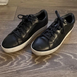 Vagabond sneakers - Stilrena svarta sneakers från vagabond i läder-look med klassisk vit sula och svarta skosnören. Snygg minimalistisk design som passar till det mesta. Lågt skaft och diskreta sömmar ger en clean vibe. Den högra skon är lite sönder där bak som man ser på sista bilden, därav priset