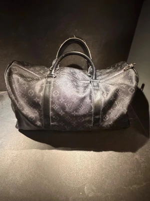 Svart kepal väska ifrån Louis Vuitton  - Hejsan! Jag säljer nu dessa riktigt feta väskan ifrån Louis Vuitton i storlek 45. Den är i väldigt bra skick förutom att de ena handtaget är lite slitet! Har tyvärr inte kvar axelbandet till den! Hör Järna av er om ni har frågor! Äkta!!!