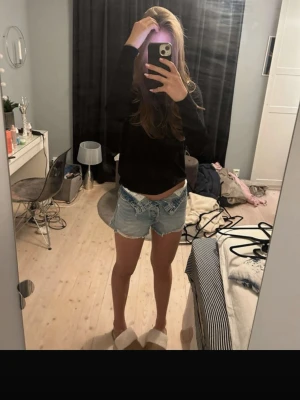 Ljusblå denimshorts Zara  - Säljer ett par ljusblå jeansshorts med råa franskantade benslut och klassisk femficksdesign. Shortsen har låg midja och slitna detaljer framtill för en avslappnad look. Perfekta till sommaren och lätta att matcha med olika toppar.