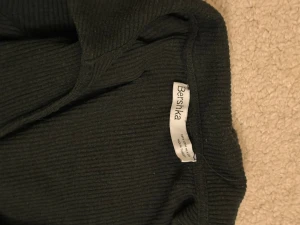 Grön ribbad jumpsuit från Bershka - Snygg svart ribbad jumpsuit från Bershka med långa ärmar och långa ben. Materialet är stretchigt och mjukt, vilket gör den riktigt bekväm. Perfekt för dig som vill ha en enkel men trendig look. Midjan är markerad för en schysst siluett.