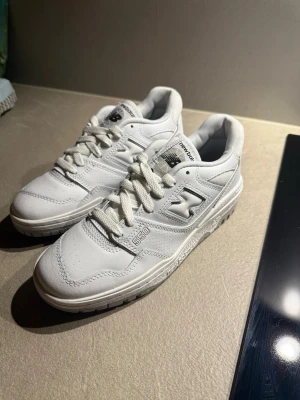 Vita New Balance 550 sneakers - Säljer ett par helt nya klassiska vita New Balance 550 sneakers i läder med snygga detaljer och broderad logga på sidan. Skorna har en chunky sula och perforerade partier för extra ventilation. Perfekta för dig som gillar retrostil och streetwear. Öppen för bud!